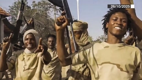 A group of men wearing khaki camouflage T-shirts celebrate raising assault rifles in the air.