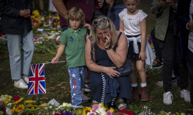 A woman cries next to flowers and messages for Queen Elizabeth II at the Green Park memorial, near Buckingham Palace, in London.