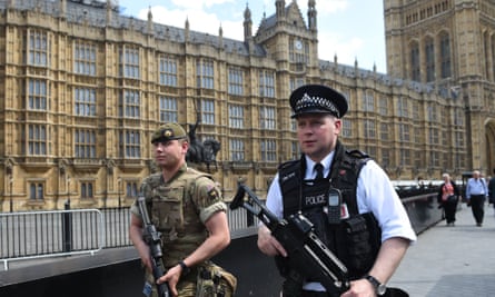 Soldiers and armed police patrol near the Houses of Parliament.