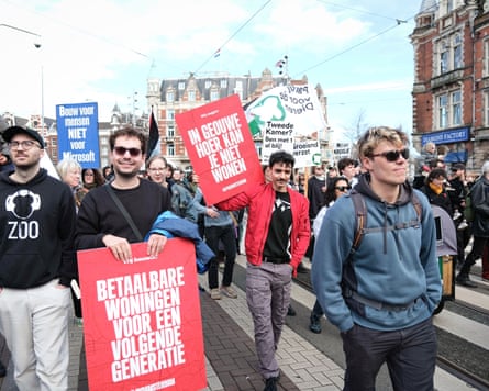 A crowd of people walking through the city holding placards