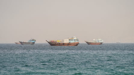 Small vessels with goods strapped to their decks at anchor.