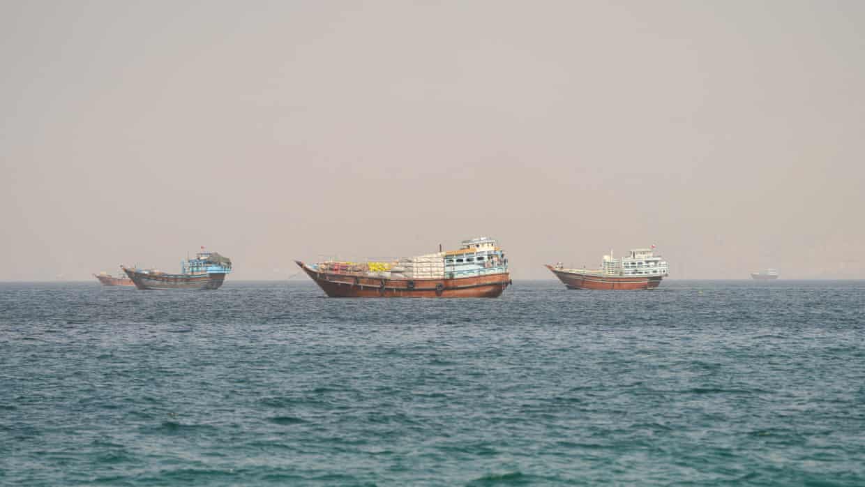 Small vessels with goods strapped to their decks at anchor.