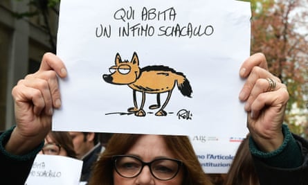 A journalist holds a placard reading ‘Here lives a vulgar jackal’ in a Milan protest.