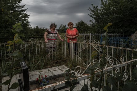 Two women in a cemetery to maintain their relatives’ graves and pay their respects under a very overcast sky