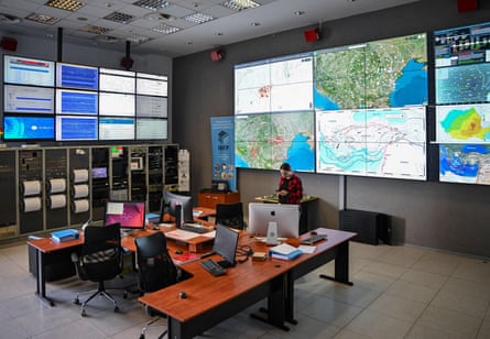 Room with electronic equipment and large screens showing maps and data