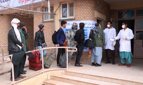 Afghan health officials screen passengers entering Afghanistan from Iran at the border in Herat