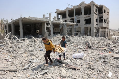 Palestinian girls carry salvaged items across debris and rubble in the al-Tuffah neighbourhood of Gaza City.