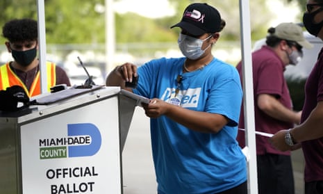 Election worker stamps a voter’s vote-by-mail ballot before placing it in an official ballot drop box in Florida.