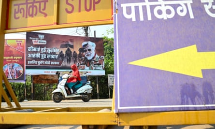A woman drives past a poster of Narendra Modi