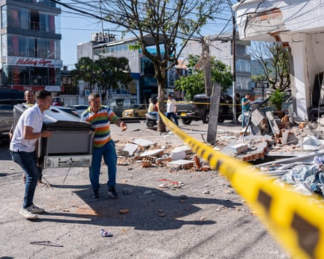 People remove a refrigerator from a damaged home in Pereira