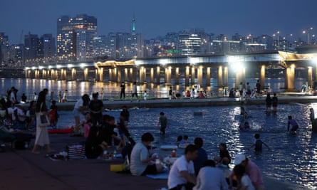 People cool off in a public park alongside the Han River in Seoul, South Korea, 31 July 2023, as a sweltering heat wave grips the country.