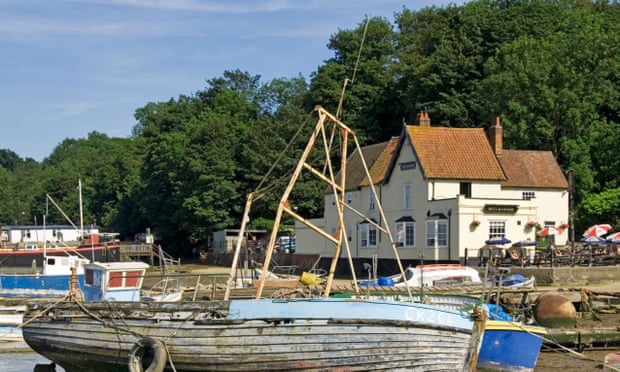 Boats in front of the Butt and Oyster Inn at Pin Mill Chelmondiston beside the River Orwell with people at outdoor tables