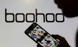 A person stands in front of a Boohoo logo.