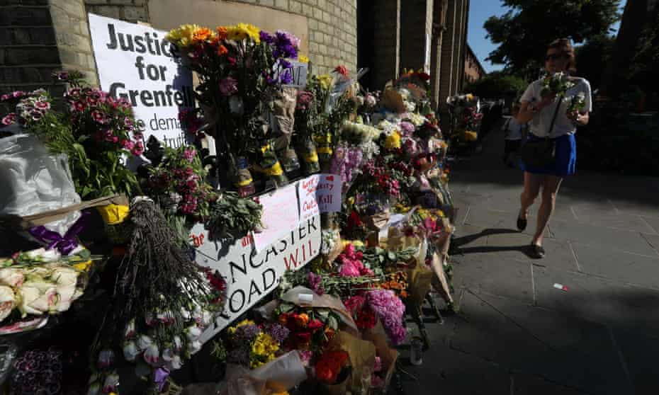 People walk past floral tributes outside Notting Hill Methodist church, near Grenfell Tower in west London.