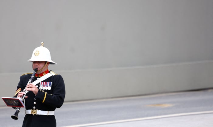 A member of a military marching band walks outside the Westminster Abbey.