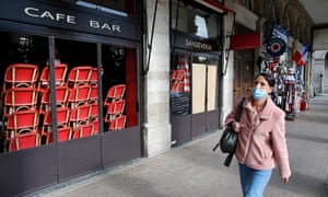 A woman wearing a protective face mask walks past a closed cafe at a nearly empty Rue de Rivoli on October 15, 2020 in Paris, France.