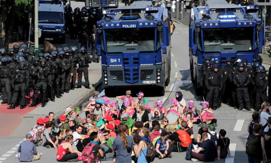 Protesters sit in front of police water cannon vehicles during the G20 summit in Hamburg.