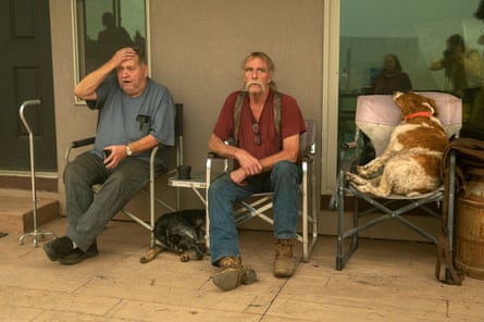 Gould Fickardt, 71, left, and Woody Hovland, 70, of Greenville, sit with their dogs, Primer, right, and Sheva, left, outside a home where they are staying after losing their own homes to the Dixie fire.