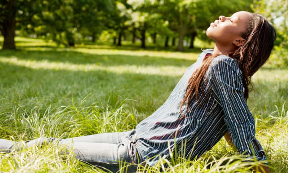 A young woman soaking up the sun in a park.