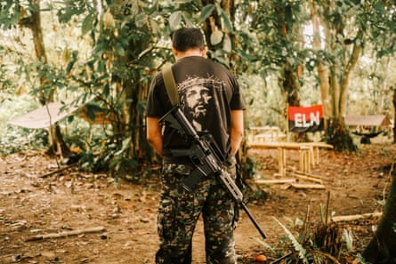 An ELN member wearing a T-shirt with the image of Jesus Christ on the back and a rifle slung over his shoulder
