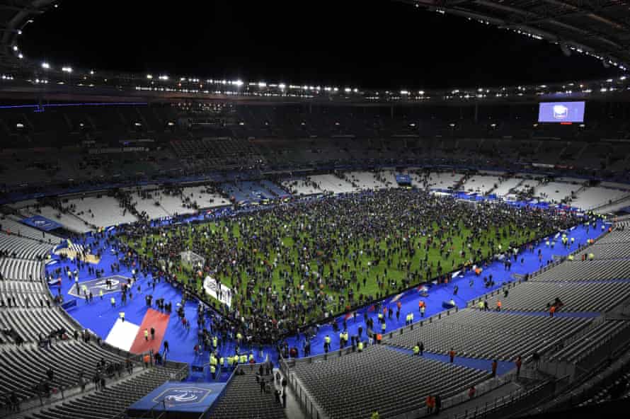 Spectators gather on the pitch of the Stade de France stadium following the match as new of the attacks emerges.