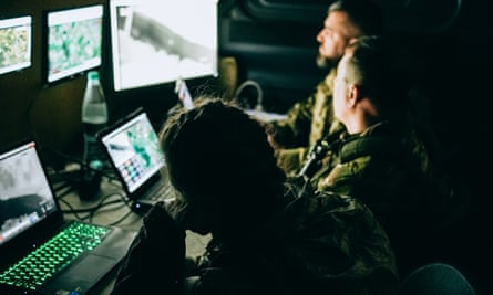Three people sit in front of computer screens