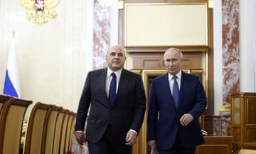 Mikhail Mishustin (left) pictured with Vladimir Putin as they head for a meeting with other officials earlier this week.