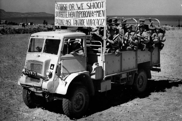 Truck has banner reading, ‘Disperse Or We Shoot’. Message in Greek underneath English.