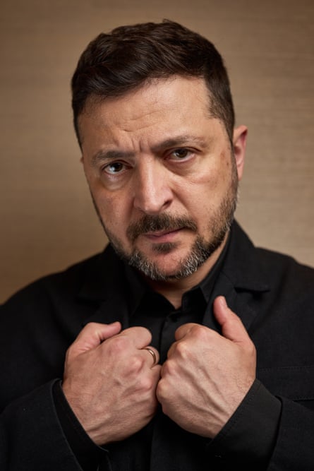 Head and shoulders portrait of Volodymyr Zelenskyy looking into camera, hands joined on chest