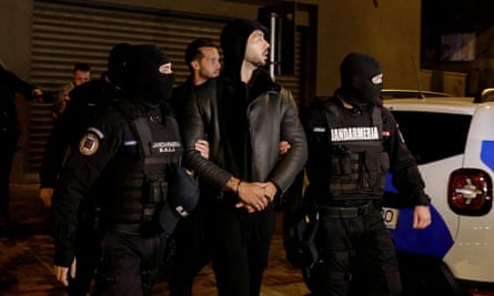 Andrew and Tristan Tate are escorted by police officers in Bucharest after being detained.