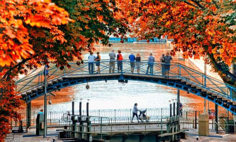 Canal St Martin in Paris, people on a bridge framed with autumn leaves