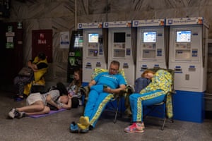 People sleep on chairs and on the ground in a metro station