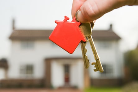 Person holding house keys in front of a home