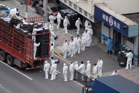 People wearing protective equipment as they transfer daily food supplies and necessities to Shanghai residents in April 2022.