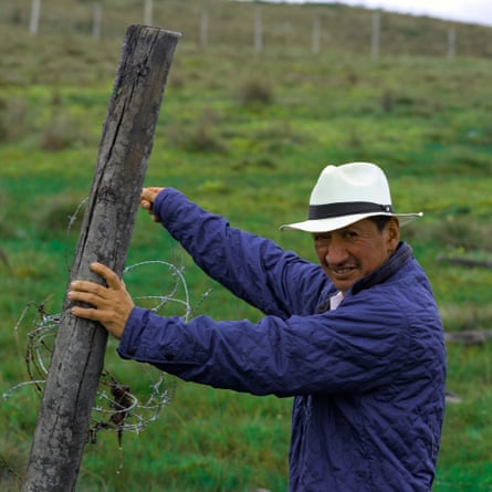 A man wearing a white fedora hat holds up a fence post