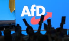 The AfD logo on a stage at a party event with crowd in the foreground