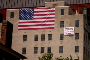 A large American flag hangs near a sign that reads “Heal Fast Big Balls Thanks, Trump!”. President Donald Trump threatened to take over Washington, D.C., after Edward Coristinea 19-year-old former Department of Government Efficiency (DOGE) staffer known online as “Big Balls” was attacked in an apparent attempted carjacking near Dupont Circle over the weekend.