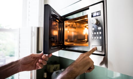 Reheating / cooking food in the microwave ovenA man using a microwave oven. His finger on the opening button.
