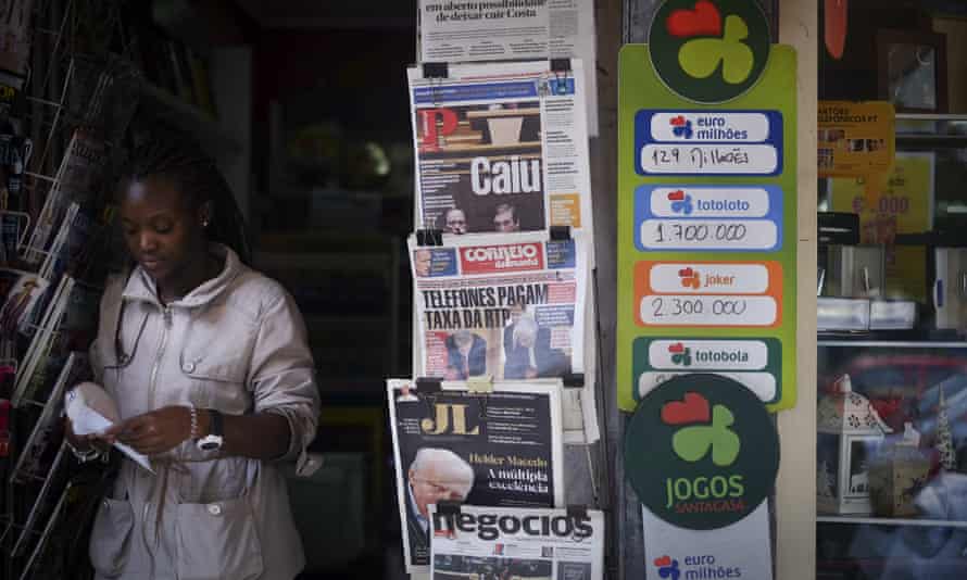 A woman leaves a kiosk displaying Portuguese newspaper front pages about the fall of the 11-day-old government.