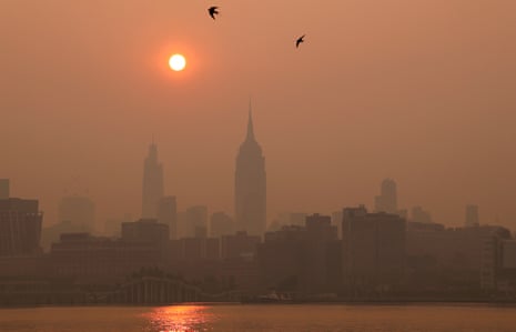 The sun is shrouded as it rises in a smoky sky behind the Empire State Building in New York City on 8 June 2023.