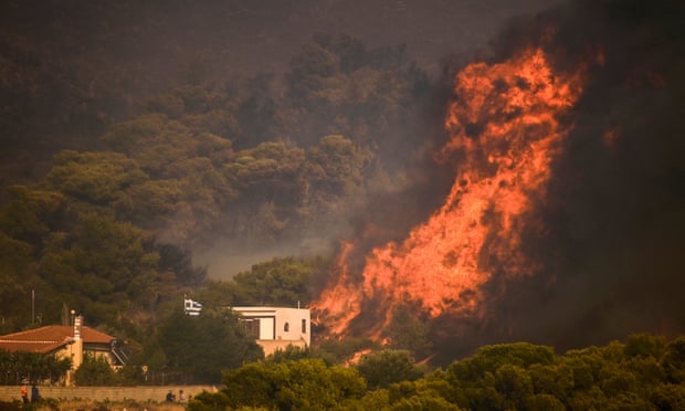 A wildfire burns next to a house in the village of Synterina, near Athens, on 16 August.