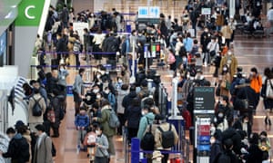 Tokyo’s Haneda airport on 28 December. People mill around in the terminal, shot from above.