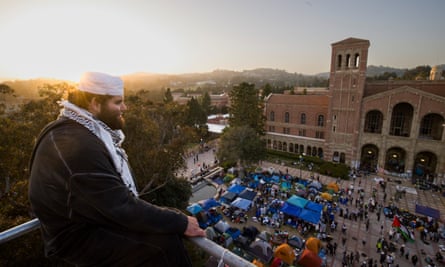A demonstrator watches the pro-Palestine encampment from a construction scaffold on the UCLA campus on Wednesday.
