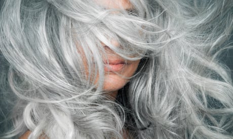 Woman with grey hair blowing across her face.