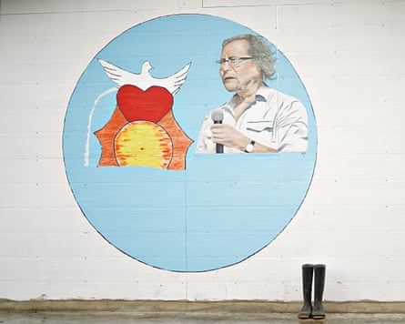 A painting on a wall of a dove and a heart with a man holding a mix who is a negotiator