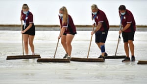 Ageas Bowl head groundsman Simon Lee (1R) and staff clear the water off the covers.