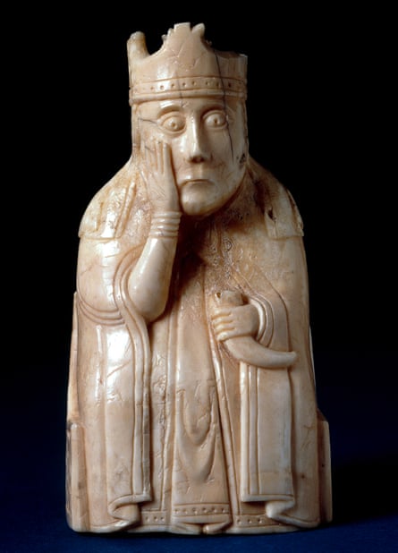 The queen from The Lewis Chessmen, British Museum. Chess-piece; walrus ivory; queen wearing floriated crown over veil, mantle; holding horn; right hand placed on cheek; seated in chair ornamented on back with adjacent leaf scrolls with animal-heads on top of uprights; chair sides: interlace ornament.
