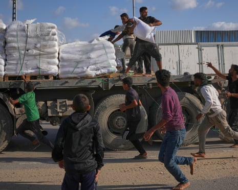People grab sacks of flour from a moving lorry