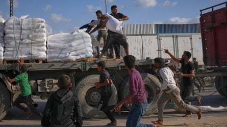 People grab sacks of flour from a moving lorry carrying World Food Programme aid in Gaza.