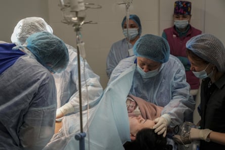 Medical workers hold newborn Alana close to her mother after a caesarean section at a hospital in Mariupol, 11 March